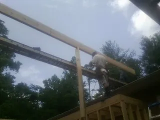 Carpenter setting a ridge beam over a new addition frame — Ice Dam Removal by Roofing Brothers in Como